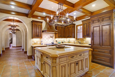This is an example of a large mediterranean u-shaped open plan kitchen in San Francisco with an undermount sink, raised-panel cabinets, dark wood cabinets, limestone benchtops, beige splashback, stone tile splashback, stainless steel appliances, terra-cotta floors and with island.