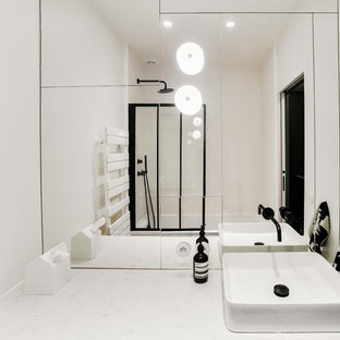 Imagen de cuarto de baño con ducha, actual, de tamaño medio, con armarios con paneles lisos, puertas de armario de madera clara, bañera encastrada sin remate, combinación de ducha y bañera, baldosas y/o azulejos blancos, baldosas y/o azulejos con efecto espejo, paredes blancas, suelo de azulejos de cemento, lavabo sobreencimera, encimera de cuarcita, suelo negro, ducha con puerta con bisagras y encimeras beige