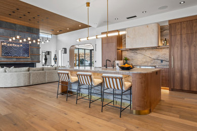Example of a trendy galley medium tone wood floor and brown floor kitchen design in Salt Lake City with flat-panel cabinets, dark wood cabinets, brown backsplash, stone slab backsplash, stainless steel appliances, an island and brown countertops
