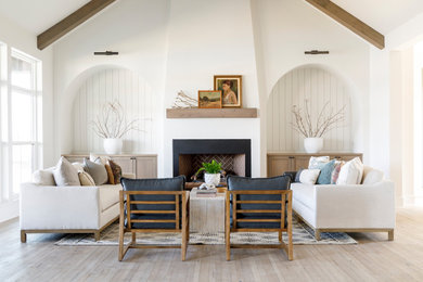 Example of a mid-sized cottage medium tone wood floor, vaulted ceiling and shiplap wall living room design in Boise with white walls, a standard fireplace and a plaster fireplace