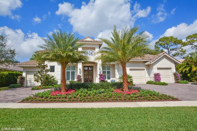 Large tropical beige two-story stucco house exterior idea in Miami with a hip roof and a tile roof