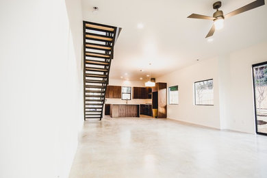 Example of a mid-sized minimalist concrete floor open concept kitchen design in Austin with a farmhouse sink, flat-panel cabinets, medium tone wood cabinets, quartz countertops, stainless steel appliances and an island