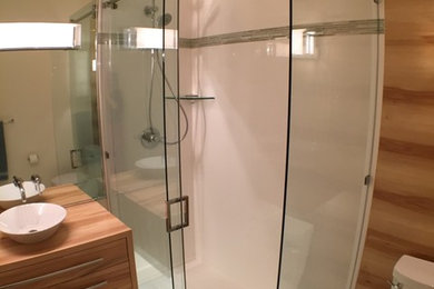 Mittelgroßes Modernes Duschbad mit flächenbündigen Schrankfronten, hellbraunen Holzschränken, offener Dusche, Wandtoilette mit Spülkasten, weißer Wandfarbe, Keramikboden, Aufsatzwaschbecken, Waschtisch aus Holz, grauem Boden und Schiebetür-Duschabtrennung in Vancouver