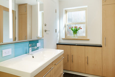 Ejemplo de cuarto de baño principal, único y flotante actual de tamaño medio con armarios con paneles lisos, puertas de armario de madera clara y encimeras blancas