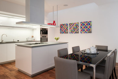 This is an example of a contemporary eat-in kitchen in London with with island.