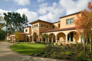 Large mediterranean two-storey stucco beige house exterior in San Francisco with a gable roof and a tile roof.