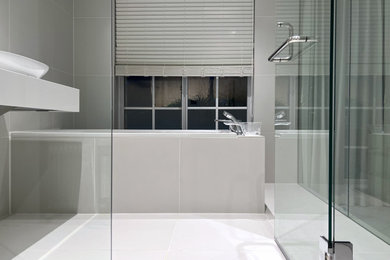 東京23区にある中くらいなモダンスタイルのおしゃれなマスターバスルーム (白いキャビネット、ドロップイン型浴槽、シャワー付き浴槽	、グレーのタイル、磁器タイル、磁器タイルの床、ペデスタルシンク、グレーの床、開き戸のシャワー、白い洗面カウンター、洗面台1つ、フローティング洗面台、グレーとクリーム色) の写真