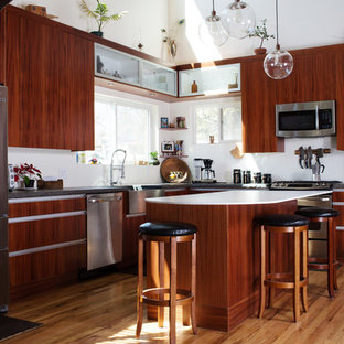 Mid-sized contemporary kitchen pantry inspiration - Inspiration for a mid-sized contemporary l-shaped light wood floor kitchen pantry remodel in Albuquerque with a farmhouse sink, flat-panel cabinets, medium tone wood cabinets, granite countertops, white backsplash, stainless steel appliances and an island