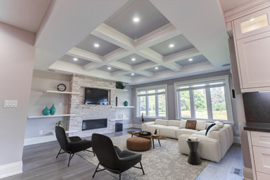 Living room - mid-sized contemporary light wood floor, gray floor and coffered ceiling living room idea in Toronto with gray walls, a standard fireplace, a stone fireplace and a wall-mounted tv