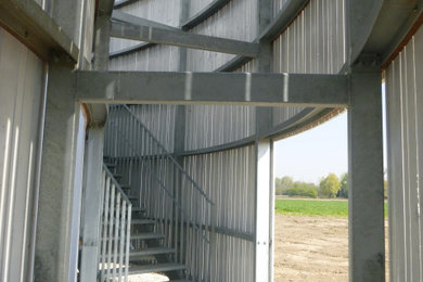 Design ideas for a curved metal railing staircase in Buckinghamshire with metal risers, wood walls and a feature wall.