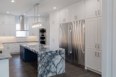 Inspiration for a contemporary u-shaped dark wood floor and brown floor kitchen remodel in Dallas with an undermount sink, recessed-panel cabinets, white cabinets, granite countertops, white backsplash, ceramic backsplash, stainless steel appliances, an island and gray countertops
