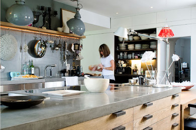 Foto på ett mellanstort industriellt kök med öppen planlösning, med en rustik diskho, släta luckor, skåp i mellenmörkt trä, bänkskiva i betong, grått stänkskydd, rostfria vitvaror, ljust trägolv och en köksö