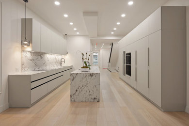 ニューヨークにある高級な広いコンテンポラリースタイルのおしゃれなキッチン (フラットパネル扉のキャビネット、白いキャビネット、シルバーの調理設備) の写真