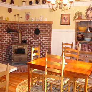 ウィルミントンの広いカントリー風 LDKの画像 (黄色い壁、無垢フローリング、薪ストーブ、レンガの暖炉まわり)