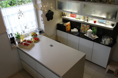 Diseño de cocina minimalista con encimera de laminado, salpicadero negro, puertas de granito, península y encimeras beige