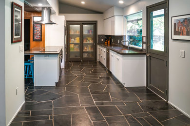 Example of a mid-sized 1960s single-wall open concept kitchen design in Other with an undermount sink, stainless steel appliances, flat-panel cabinets, white cabinets, multicolored backsplash, ceramic backsplash and an island
