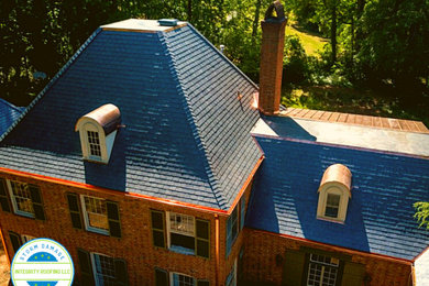 Large traditional brown two-story brick house exterior idea in Charlotte with a hip roof and a tile roof