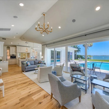 Open Waterfront Living Room With Vaulted Ceiling, Sliding Glass Wall, and Poolsi