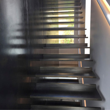 Floating steel staircase and blackened steel wall