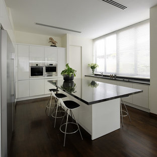 Mid-sized contemporary kitchen pantry designs - Example of a mid-sized trendy dark wood floor kitchen pantry design in Singapore with white cabinets and an island