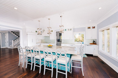 Inspiration for a mid-sized transitional u-shaped dark wood floor and brown floor open concept kitchen remodel in Other with a farmhouse sink, recessed-panel cabinets, white cabinets, marble countertops, gray backsplash, ceramic backsplash, paneled appliances, an island and beige countertops