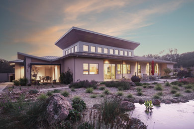 Example of a large minimalist beige one-story stucco house exterior design in San Francisco with a metal roof and a gray roof