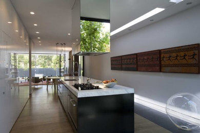Design ideas for a contemporary single-wall eat-in kitchen in Melbourne with an undermount sink, recessed-panel cabinets, marble benchtops, black appliances, light hardwood floors, with island, beige floor and dark wood cabinets.