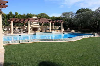 Example of a large trendy backyard stone and rectangular infinity hot tub design in Los Angeles