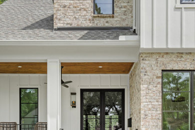 Inspiration for a large transitional white two-story brick and board and batten exterior home remodel in Houston with a shingle roof and a black roof
