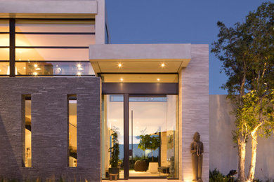 Photo of an expansive contemporary two-storey beige house exterior in Los Angeles with stone veneer and a flat roof.