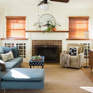 Fernseherlose Mediterrane Bibliothek mit weißer Wandfarbe, hellem Holzboden, Kamin, gefliestem Kaminsims und beigem Boden in Portland