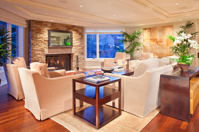 Example of a large trendy open concept medium tone wood floor living room design in Denver with a standard fireplace, a stone fireplace, a concealed tv and beige walls