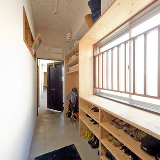 大阪の片開きドアアジアンスタイルのおしゃれな玄関ホール (白い壁、コンクリートの床、グレーの床、黒いドア) の写真