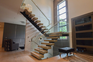 Diseño de escalera moderna con escalones de madera, contrahuellas de metal y barandilla de vidrio