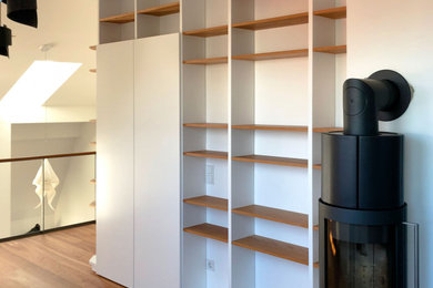Moderne Bibliothek im Loft-Stil mit dunklem Holzboden, Hängekamin, verstecktem TV und braunem Boden in München