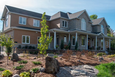 This is an example of a traditional drought-tolerant and full sun front yard stone retaining wall landscape in Ottawa.