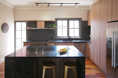 Mid-sized contemporary l-shaped kitchen pantry in Melbourne with a double-bowl sink, medium wood cabinets, quartz benchtops, black splashback, ceramic splashback, black appliances, medium hardwood floors and with island.