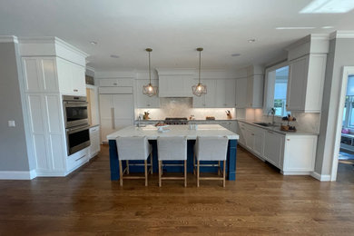 Mid-sized transitional medium tone wood floor and brown floor kitchen photo in Boston with a single-bowl sink, shaker cabinets, white cabinets, white backsplash, subway tile backsplash, stainless steel appliances and an island