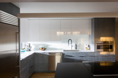 Example of a kitchen design in Cincinnati with an undermount sink, solid surface countertops, white backsplash, stainless steel appliances, an island and white countertops
