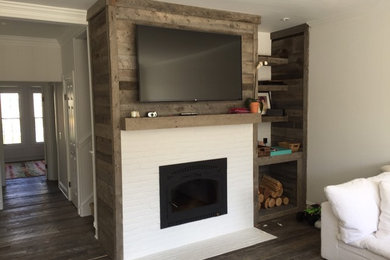 Photo of a mid-sized beach style open concept living room in Other with white walls, dark hardwood floors, a standard fireplace, a wood fireplace surround and a wall-mounted tv.