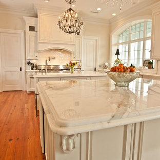 Photo of a large u-shaped kitchen pantry in Other with an undermount sink, beaded inset cabinets, white cabinets, marble benchtops, white splashback, subway tile splashback, stainless steel appliances, medium hardwood floors, with island, orange floor and white benchtop.