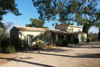 Cette image montre une grande façade de maison beige rustique en stuc à un étage avec un toit à deux pans et un toit en tuile.