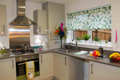 Photo of a medium sized eclectic l-shaped open plan kitchen in Kent with grey cabinets, granite worktops, metallic splashback, metal splashback, integrated appliances, no island, grey worktops and a single-bowl sink.