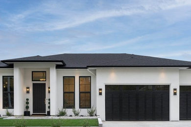 Ejemplo de fachada de casa blanca y negra minimalista extra grande de tres plantas con revestimiento de estuco, tejado a dos aguas y tejado de teja de madera