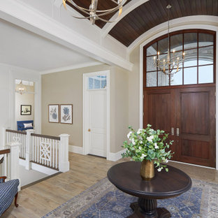 Eingang mit Foyer, beiger Wandfarbe, dunklem Holzboden, Doppeltür, dunkler Holztür, braunem Boden, gewölbter Decke, Wandpaneelen und Treppe in Grand Rapids