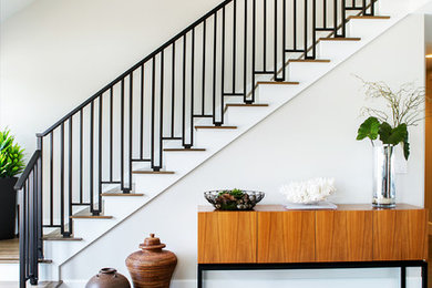 Mid-sized contemporary wood l-shaped staircase in Orange County with painted wood risers and metal railing.