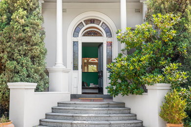 This is an example of a large traditional foyer in Melbourne with green walls, medium hardwood floors, a single front door and a black front door.