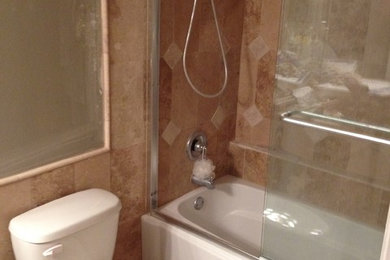 タンパにある小さなコンテンポラリースタイルのおしゃれなバスルーム (浴槽なし) (アンダーマウント型浴槽、一体型トイレ	、マルチカラーのタイル、石タイル、ベージュの壁、トラバーチンの床) の写真