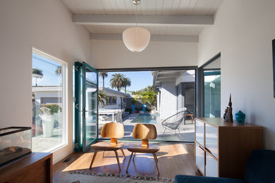 Example of a mid-sized 1950s enclosed medium tone wood floor family room design in Los Angeles with white walls and no fireplace