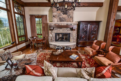 This is an example of a mid-sized country open concept living room in Denver with beige walls, light hardwood floors, a standard fireplace and a stone fireplace surround.